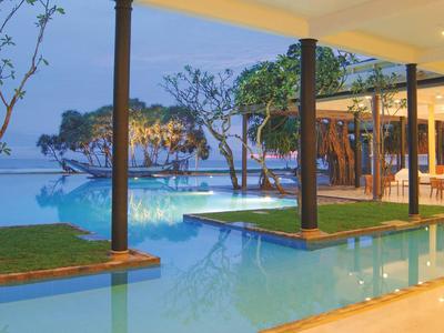 Moderner, offener Poolbereich mit Blick auf das Meer und begrünten Inseln.