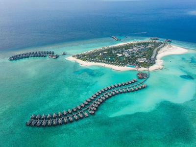 Luftaufnahme einer tropischen Insel mit Bungalows über türkisfarbenem Wasser.