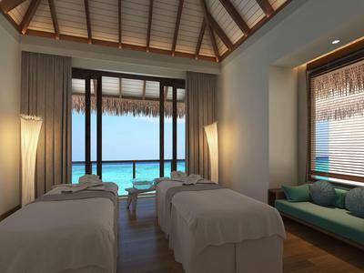 Gemütlicher Spa-Raum mit zwei Massageliegen, Meeresblick und weicher Beleuchtung.