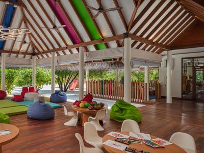 Modernes Lounge-Bereich mit bunten Sitzsäcken, Holzbalkendecke und Zugang zu einer Terrasse.