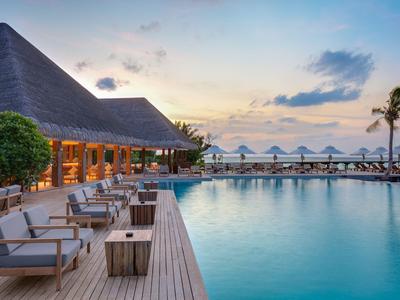 Luxuriöser Hotelpool bei Sonnenuntergang mit Liegestühlen und Palmen