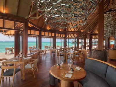 Luxuriöses Restaurant mit Holzmöbeln und Meerblick durch große Fenster.