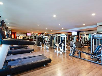 Moderner Fitnessraum mit Laufbändern und Kraftgeräten auf Holzboden in hellem Raum.