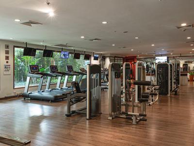 Moderner Fitnessraum mit Holzboden, Laufbändern und Kraftgeräten in einem Hotel.