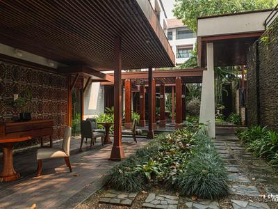 Ein gemütlicher Außenbereich mit Holzmöbeln und einer begrünten Steinwegfläche.