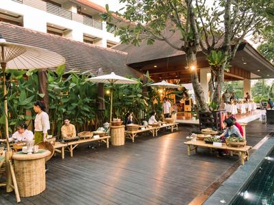 Lounge-Bereich eines Hotels mit Holzliegen, Sonnenschirmen und Pool im Freien.