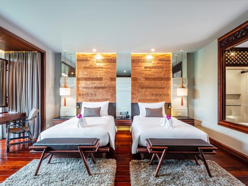 Modernes Hotelzimmer mit zwei Einzelbetten, Holzverkleidung und großem Spiegel an der Wand.