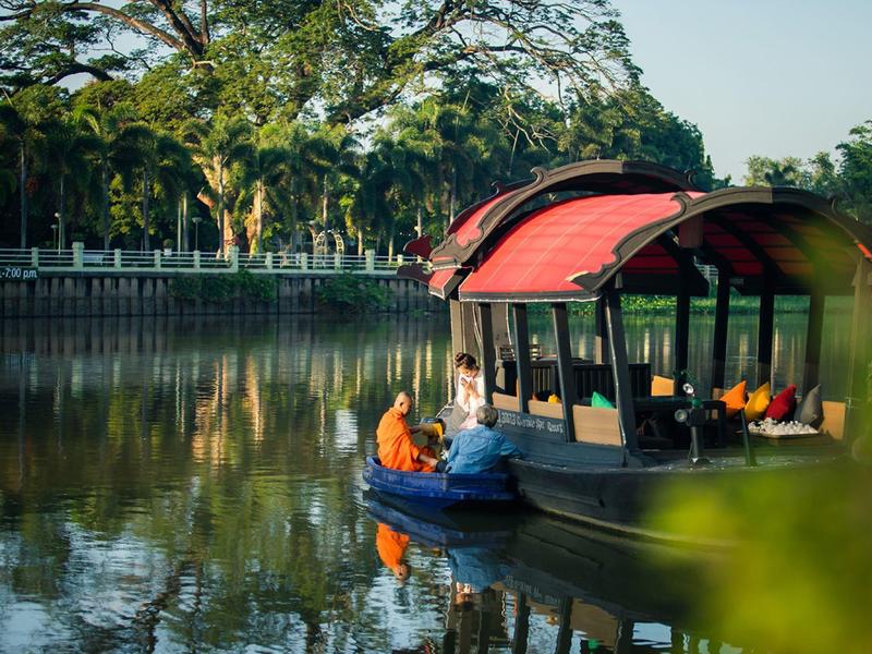 Gemütliches Bootsfahren auf ruhigem Fluss mit Passagieren unter grünem Blätterdach.
