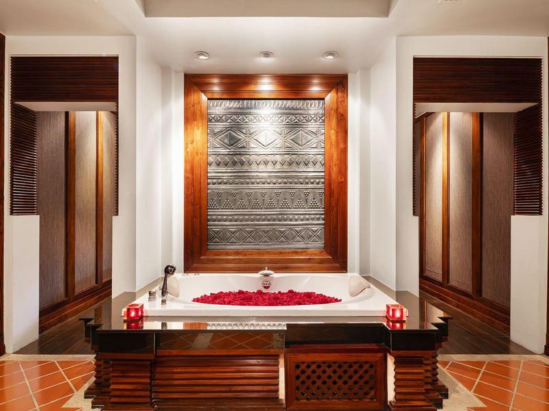 Luxuriöse Badewanne mit Rosenblättern in elegant gestaltetem Badezimmer.