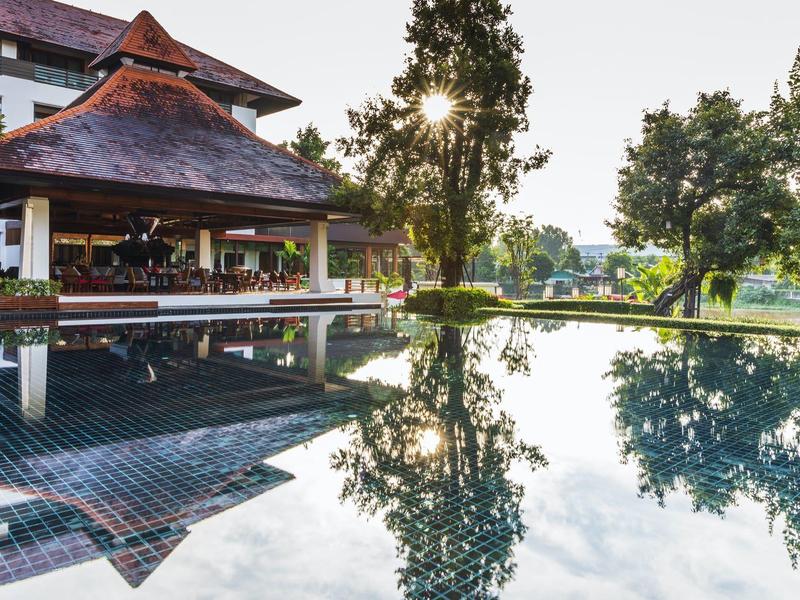Moderner Pavillon neben einem Pool mit Bäumen und Sonnenlicht im Hintergrund.