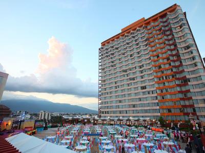 Hochhaus neben einem festlich gedeckten Außenbereich mit Blick auf Berge und Himmel bei Sonnenuntergang.