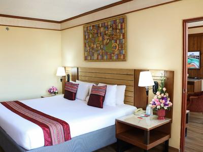 Modernes Hotelzimmer mit großem Bett, Nachttisch und Blumendekoration.