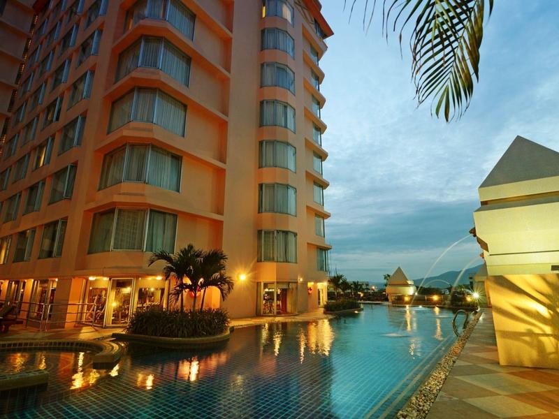 Moderner Hotelkomplex mit beleuchtetem Pool und Palmen bei Sonnenuntergang