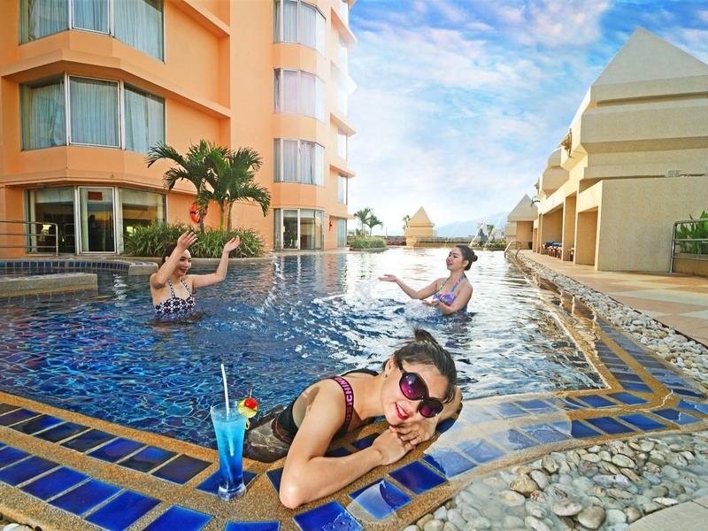 Menschen entspannen im Pool eines Hotels mit Palmen und moderner Architektur.