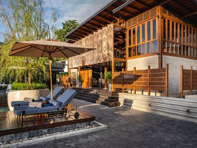 Modernes Ferienhaus mit Terrasse, Sonnenliegen und großem Sonnenschirm bei Sonnenuntergang.