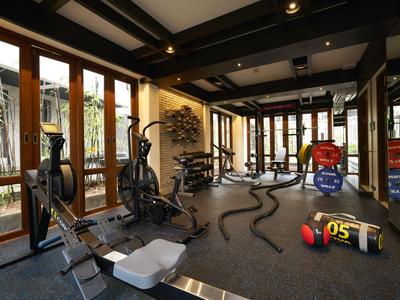 Moderner Fitnessraum mit verschiedenen Trainingsgeräten und großen Fenstern.