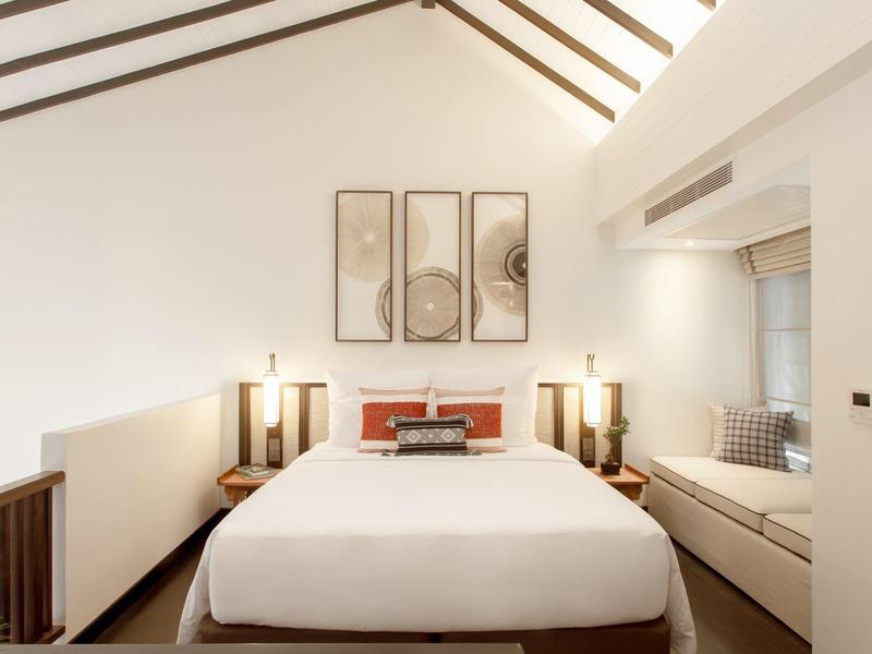 Gemütliches Schlafzimmer mit Dachschräge, großem Bett und moderner Beleuchtung.