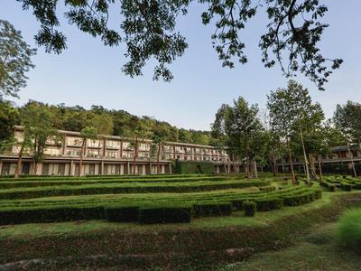 Großes Hotelgebäude mit gepflegtem Garten und dekorativem Heckenmuster bei klarem Himmel.
