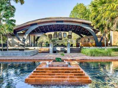 Moderner, offener Pavillon mit Wasserbecken und Treppen im tropischen Hotelgarten.