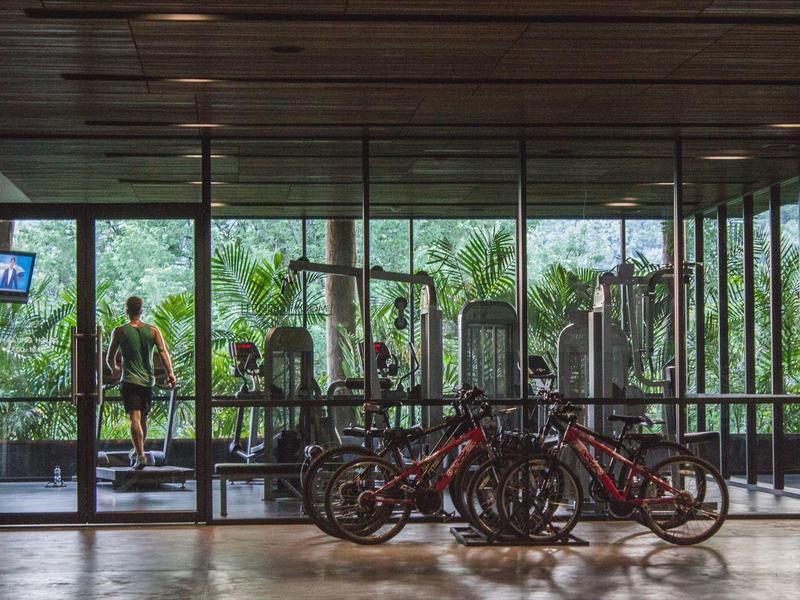 Fitnessraum mit Fahrrädern und Blick auf Garten durch große Glasfenster