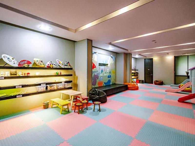 Bunter Kinderspielbereich mit Spielzeugregalen, kleinen Tischen und Sitzgelegenheiten in einem Raum.