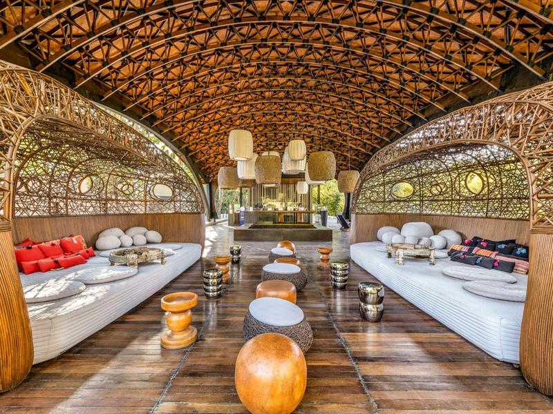 Offener Lounge-Bereich mit geschwungenem Holzdesign und Sitzkissen in warmen Tönen.