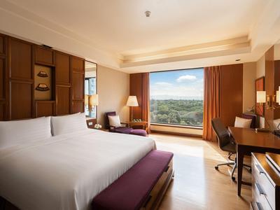 Modernes Hotelzimmer mit Doppelbett, Schreibtisch und großem Fenster mit Aussicht auf die Natur.