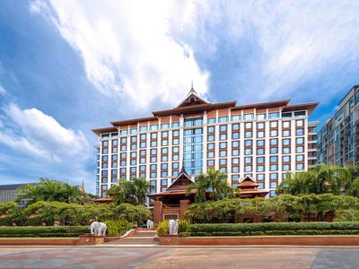 Großes Hotelgebäude mit asiatischem Architekturstil und gepflegtem Garten bei bewölktem Himmel