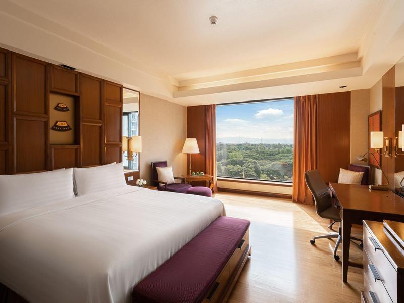 Modernes Hotelzimmer mit Doppelbett, Schreibtisch und großem Fenster mit Aussicht auf die Natur.