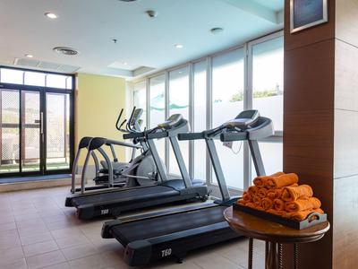 Moderner Fitnessraum mit Laufbändern und elliptischem Trainer neben großen Fenstern.