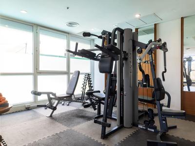 Moderne Fitnessgeräte in einem hellen, gut ausgestatteten Fitnessraum mit großen Fenstern.