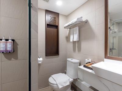 Moderner Badezimmerbereich mit Toilette, Handtüchern und Waschbecken in einem Hotelzimmer.