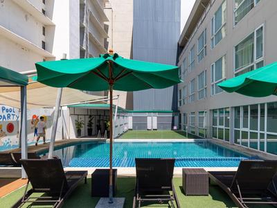 Moderner Außenpool in einem Hotel mit Liegestühlen und grünen Sonnenschirmen.