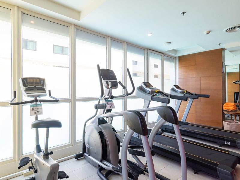 Moderner Fitnessraum mit Laufbändern und Fahrradergometern vor großen Fenstern.