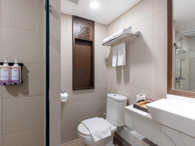 Moderner Badezimmerbereich mit Toilette, Handtüchern und Waschbecken in einem Hotelzimmer.