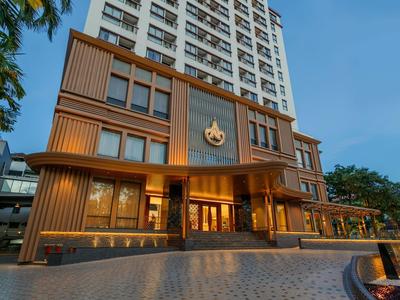 Modernes Hotelgebäude mit warm beleuchtetem Eingang und hoher Fassade bei Dämmerung.