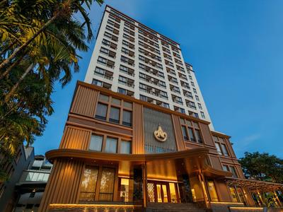 Moderner, mehrstöckiger Hotelkomplex mit Palmen, Holzfassade und blauem Himmel im Hintergrund.