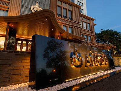 Außenansicht eines Hotels mit beleuchtetem Namensschild bei Dämmerung.