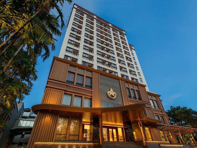 Moderner, mehrstöckiger Hotelkomplex mit Palmen, Holzfassade und blauem Himmel im Hintergrund.