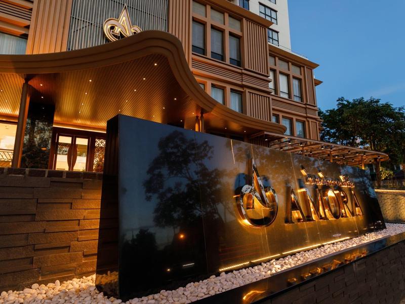 Außenansicht eines Hotels mit beleuchtetem Namensschild bei Dämmerung.