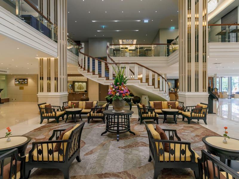 Elegante Hotellobby mit Sitzbereich, Teppich und Treppe im Hintergrund.