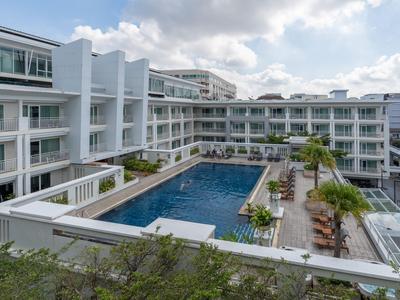 Modernes Hotel mit großem Außenpool und Sonnenliegen auf der Terrasse.