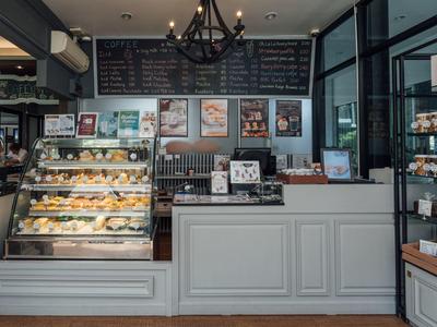 Modernes Café mit beleuchtetem Kuchentheken und einer großen Auswahl an Gebäck und Getränken.