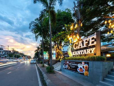 Straße mit Café-Kantary-Schild bei Sonnenuntergang und Palmen beleuchtet.