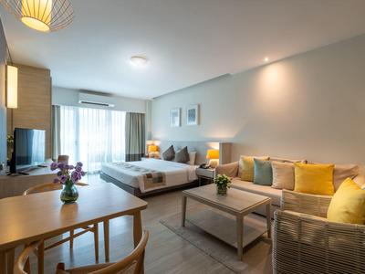 Hell eingerichtetes Hotelzimmer mit Doppelbett, Sofa und Esstisch.