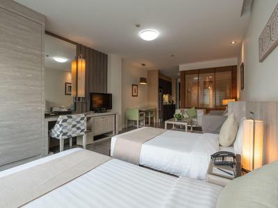 Modern eingerichtetes Hotelzimmer mit zwei Betten, einem Schreibtisch und einer Minibar.