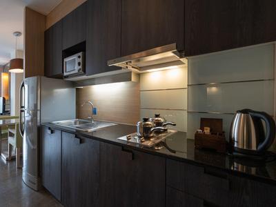 Moderne Küchenzeile mit dunklem Holz, Herd, Mikrowelle und Wasserkocher in einem Apartment.