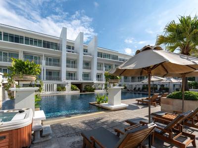 Espace piscine moderne d'hôtel avec chaises longues et parasols sous un ciel clair.