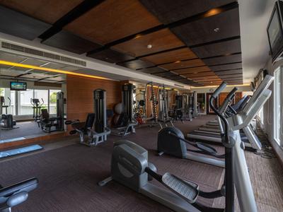 Moderner Fitnessraum mit mehreren Trainingsgeräten und großen Fenstern mit Blick nach draußen.