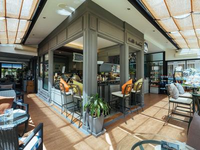 Gemütliche Außenterrasse eines Cafés mit Stühlen, Tischen und dekorativen Pflanzen.